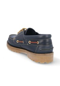Zapato náutico de cuero azul marino con punta redonda, costuras crema, ojales dorados y suela de goma. Presenta un diseño de perfil bajo.