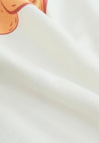 Tela de algodón con una textura suave, que presenta una base blanca y un sutil diseño impreso en tonos naranjas y rosas.