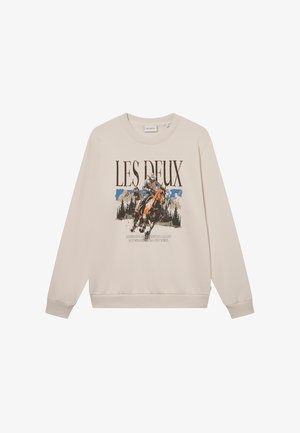 Beżowa bluza z długim rękawem, okrągłym dekoltem i grafiką z przodu przedstawiającą jeźdźca konnego oraz góry. Miękki materiał, luźny krój.