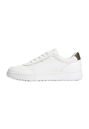 Witte lage sneaker met veters, geperforeerde kraag, groene hieltab en Tommy Hilfiger-logo aan de zijkant.
