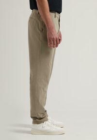 Beige chinos laget av bomullsblanding, slim fit, med sidelommer, frontlukking med knapp, og oppbrettede mansjetter, kombinert med hvite joggesko.