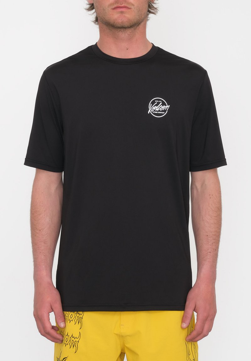 Camiseta negra de manga corta hecha de un tejido suave, con un logotipo gráfico blanco en el lado izquierdo del pecho y un diseño de cuello redondo.