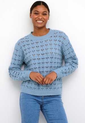 Maglione azzurro chiaro lavorato a maglia con motivo traforato, polsini a costine e collo rotondo, abbinato a jeans blu.