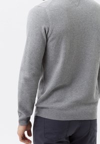 Pull en tricot gris avec un motif texturé, col rond et bords côtelés aux poignets et à l'ourlet. Le matériau semble doux et légèrement extensible.
