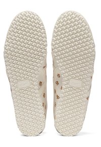 Semelles blanches de baskets avec une texture en motif diamant, agrémentées de petits dessins de tigres cartoon sur les côtés.