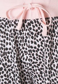 Shorts met luipaardprint, met een zwart-wit patroon en roze accenten. De elastische tailleband heeft een strikdetail aan de voorkant.