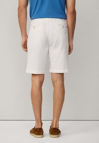 Shorts en coton blanc à coupe droite, dotés de deux poches arrière et de ourlets retroussés, associés à des mocassins en daim marron.