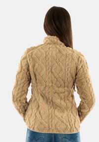 Giacca in pile beige, texturizzata, con motivo a treccia, colletto alto e tessuto morbido e soffice, vista da dietro.