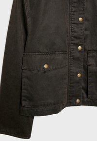 Veste marron foncé avec une surface texturée, dotée de deux poches avant, de boutons-pression et de détails de couture visibles.