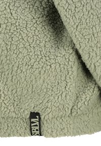 Flauschiger hellgrüner Fleece-Stoff mit strukturierter Oberfläche, an der unteren Kante mit einem schwarzen Label versehen, auf dem "SBWL" gedruckt ist.