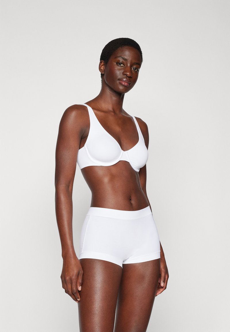 Soutien-gorge blanc à la finition lisse, avec des bretelles larges et des bonnets moulés. Accompagné de culottes garçonnes blanches assorties, dotées d'une taille élastique douce.