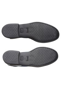 Semelles de chaussures en caoutchouc noir texturé avec la marque "Camper" et la taille 38 indiquée, présentées côte à côte sur fond blanc.