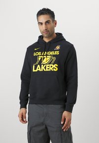 Sweatshirt preto feito de mistura de algodão, apresentando um grande logótipo amarelo "LOS ANGELES LAKERS" e um pequeno logótipo no peito, com um bolso na frente.