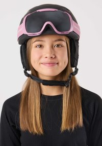 Zwarte skihelm met roze accenten en geïntegreerde skibril. Voorzien van oorbedekking en een kinband. Model draagt een zwart shirt met lange mouwen.