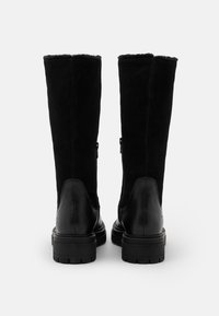 Stivali neri fino al ginocchio in suede con tacco in pelle. Presentano una suola piatta e una cerniera sul lato esterno per una facile indossabilità.
