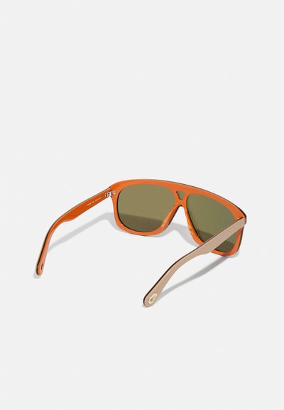 Lunettes de soleil rectangulaires orange avec des verres verts. La monture présente une finition brillante et des branches couleur brun clair contrastantes avec des accents dorés.