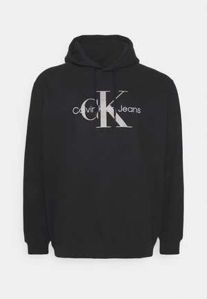Black hoodie with a drawstring, featuring a large white graphic of "CK" and "Calvin Klein Jeans" on the front. Soft fabric texture.