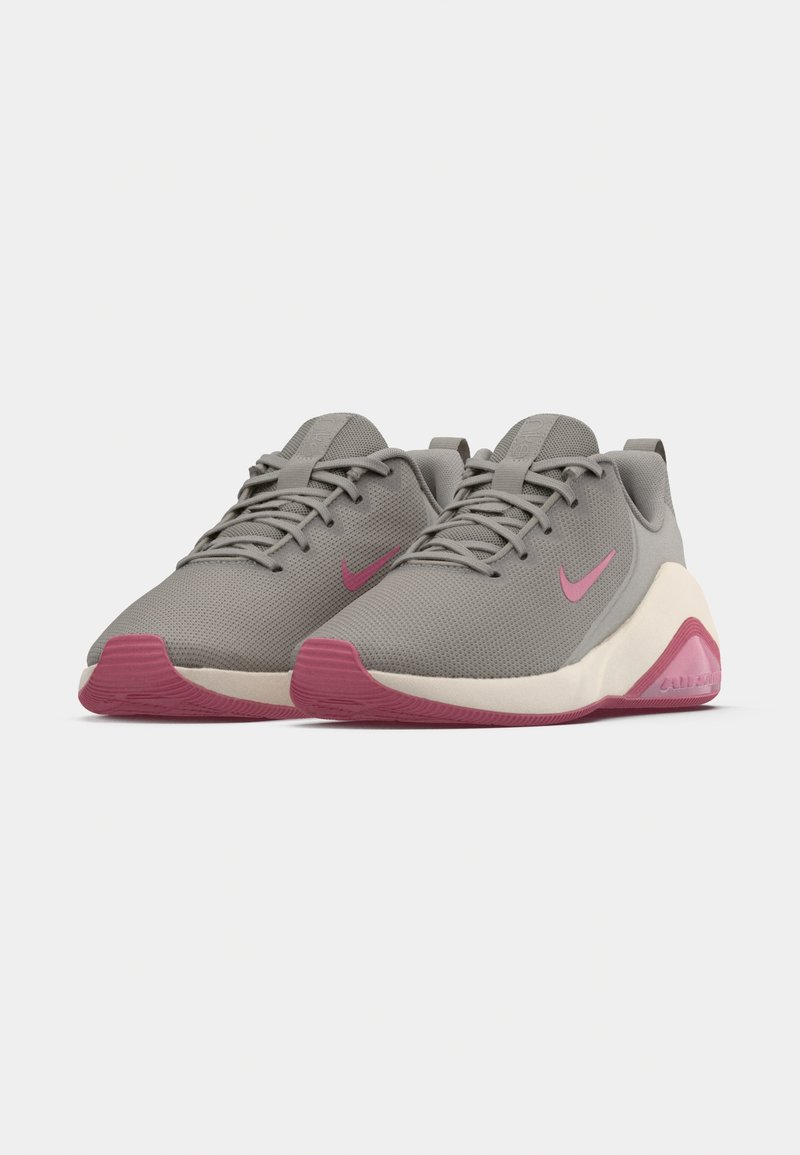 Gray athletic shoes with mesh upper, pink accents, and textured grip outsole. Features rounded toe and flat lace design.