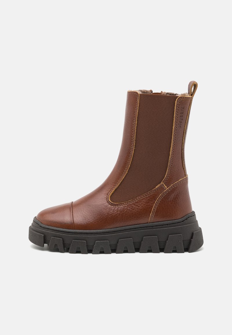 Bottine en cuir marron avec des panneaux latéraux élastiques, une semelle en caoutchouc noir épaisse et une finition texturée. Présente une languette à l'arrière.