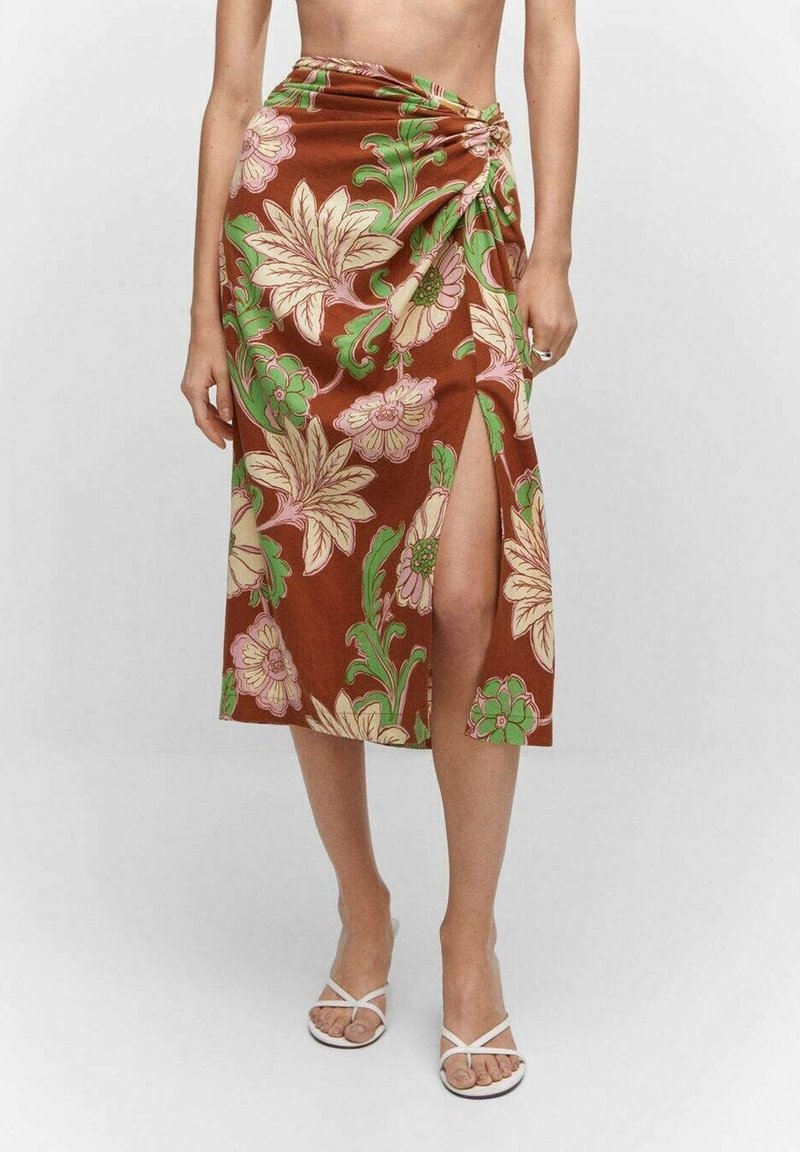 Jupe fleurie marron avec des motifs roses et verts, longueur genou avec une fente latérale et un détail de tissu froncé à la taille.