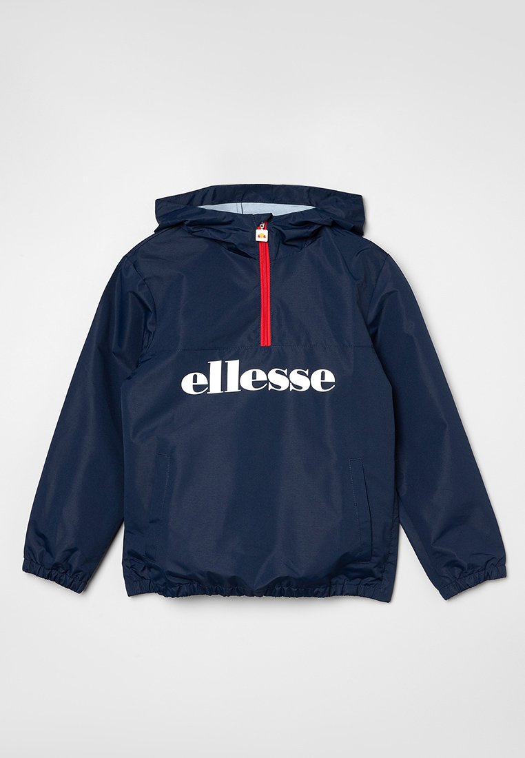 Chaqueta cortavientos con capucha en color navy, con cremallera frontal de media longitud, puños elásticos y un logo "ellesse" blanco en el pecho. Detalle de cremallera roja.