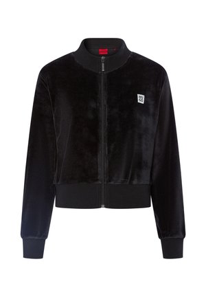 Schwarze Samtbomberjacke mit einem Reißverschluss vorne, gerippten Bündchen und Saum. Verfügt über ein kleines weißes Logo-Patch auf der linken Brust.