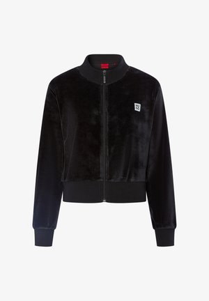 Czarna satynowa kurtka bomberka z zamkiem z przodu, prążkowanymi mankietami i pasem w talii. Posiada małą białą naszywkę z logo na lewej piersi.