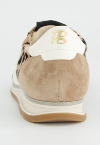 Baskets en daim beige avec une superposition à motifs blancs et noirs. Comprend un logo doré et une semelle amortie, offrant un design texturé.