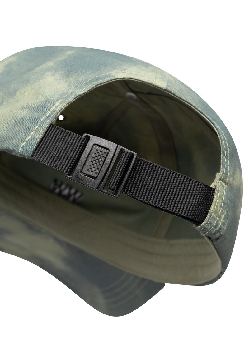 Camouflage cap with a rounded peak, made of textured fabric. Features an adjustable black strap and sewn accents in green and tan.