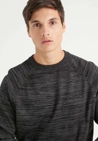 Suéter gris de punto texturizado con cuello redondo, que presenta diferentes patrones de rayas horizontales y puños acanalados.