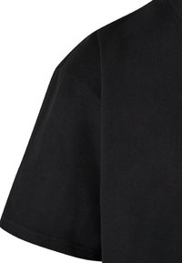 Tricou scurt negru cu mâneci scurte, fabricat din bumbac. Dispune de un gât rotund și o textură netedă, cu un design simplu; fără modele sau accente vizibile.