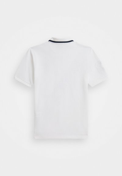 Polo blanc avec un col sombre contrastant et des manches courtes, texture lisse et détail de logo sur la manche.