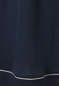 Tela azul marino con una textura suave, presenta una línea de acento blanca a lo largo del dobladillo. El diseño es simple y sin adornos.