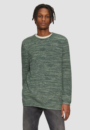 Groene gestructureerde trui met lange mouwen en een ronde hals, met een contrasterende binnenkraag, gecombineerd met grijze jeans.