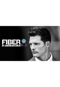 American Crew Fiber-product prominent weergegeven met een blauw en zwart etiket. Een man met gestyled donker haar, gekleed in een grijze blazer, in profiel.