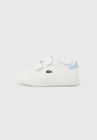 Λευκά αθλητικά παπούτσια Lacoste με λουράκια βέλκρο, με πράσινο λογότυπο κροκόδειλου στο πλάι και γαλάζια λεπτομέρεια στη φτέρνα.