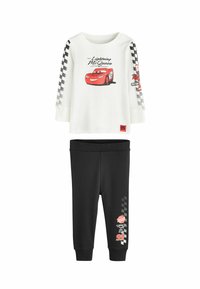 Valge pika varrukaga topp, millel on punane "Lightning McQueen" graafika ja ruudulised varrukad. Mustad püksid punaste ja ruuduliste aktsentidega.