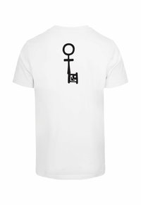 Hvid t-shirt med et stort sort nøglemotiv trykt på ryggen. Korte ærmer, rund halsudskæring og en glat stofstruktur.