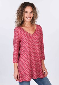 Rote gemusterte Tunika mit V-Ausschnitt und drei Viertelärmeln, die ein Blattform-Motiv zeigt. Weicher Stoff mit lockerer, fließender Passform.