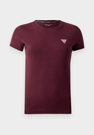 T-shirt corto a maniche corte di colore marrone con scollo tondo, caratterizzato da una piccola patch del logo Guess in rosso e bianco sul lato sinistro del petto.