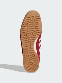 Červená teniska s textúrovanou gumovou podrážkou so vzorom rybej kosti, bielymi troma pruhmi a zvrškom zo semišu.