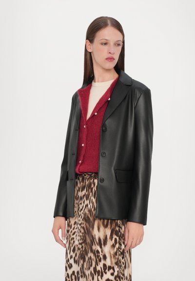 Black faux leather blazer with a notched collar, front button closure, and two pockets, worn over a burgundy textured sweater and a leopard print skirt.