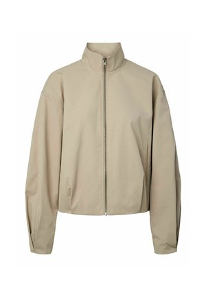Veste beige zippée avec col montant, manches longues et poches latérales, présentée sur un fond blanc.