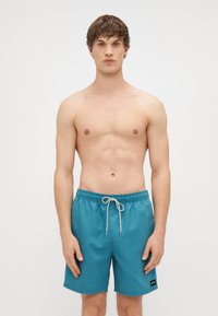 Tyrkysové plavky s elastickým pásom a šnúrkou, na ľavej strane s malou čiernou logo nášivkou.