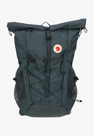 Tmavě zelený látkový batoh s rolovacím víkem, přední gumové přezky, boční síťové kapsy a nášivka s logem. Pevný a lehký design.