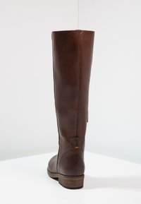 Botte haute jusqu'au genou en cuir marron à texture lisse, bout arrondi et talon en bois. Dotée d'une fermeture éclair au dos et d'un logo discret près du talon.