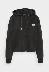 Svart, kort hoodie laget av mykt stoff, med kengurulomme, snorhette og et lite fargerikt merke på forsiden.