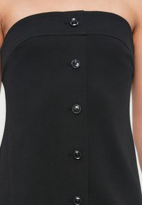 Μαύρο, στράπλες φόρεμα με εφαρμοστή μπούστο, διακοσμημένο με έξι λαμπερά μαύρα κουμπιά στο μπροστινό μέρος. Λείο, ελαστικό ύφασμα.