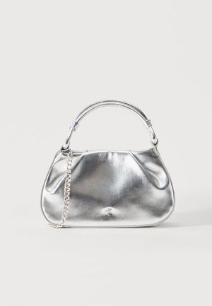 Petit sac à main métallique argenté avec une poignée courte et une chaîne comme détail, sur un fond blanc uni.