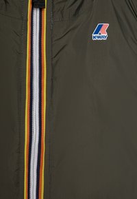Giacca leggera verde oliva con zip centrale, caratterizzata da strisce multicolori (giallo, arancione, rosso e blu) e un logo sul petto.